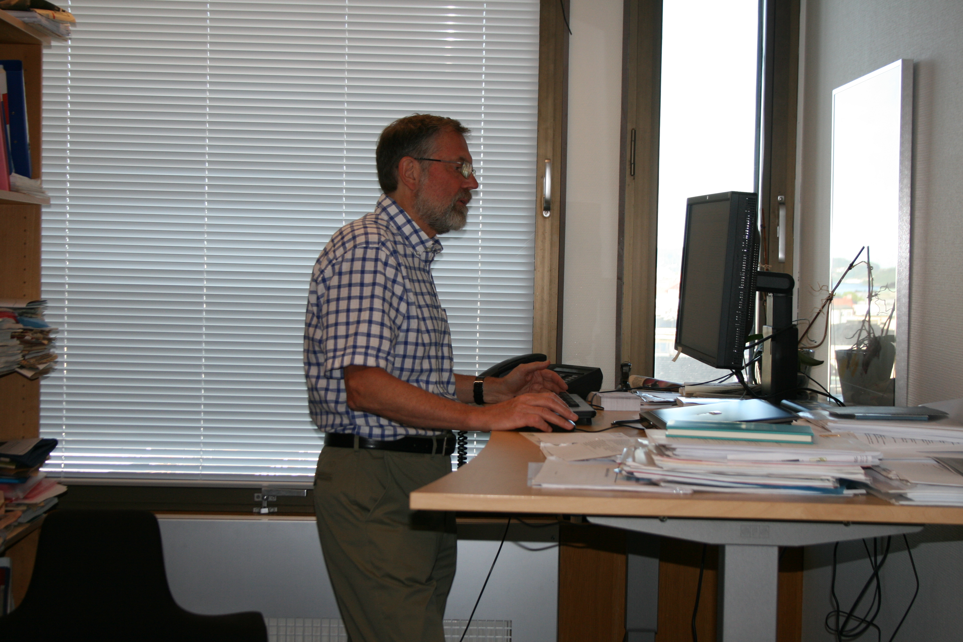 Foto av en saksbehandler som står ved skrivebordet sitt